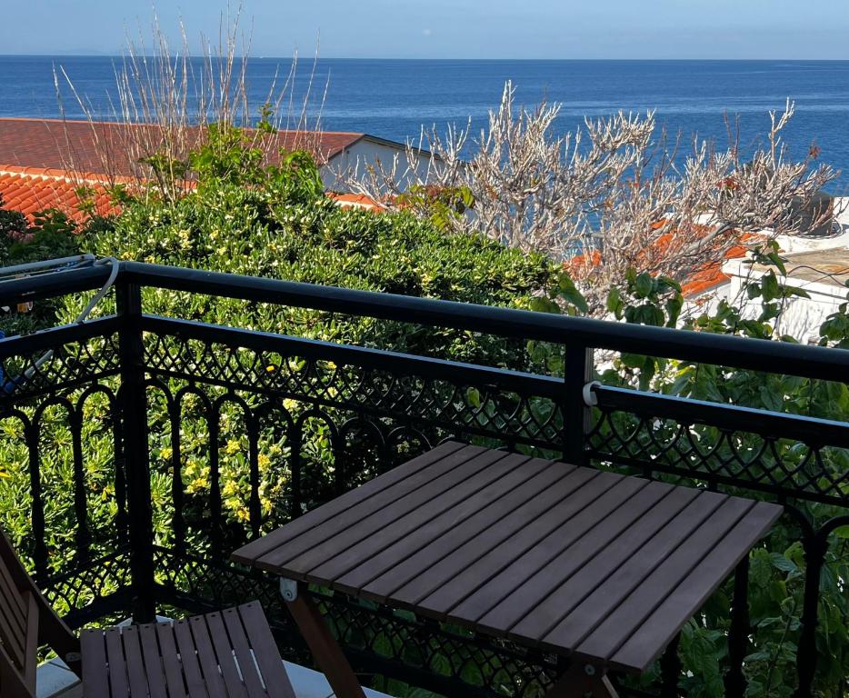 a wooden bench sitting on a balcony overlooking the ocean at Sufiko Studios - Thea in Armenistis