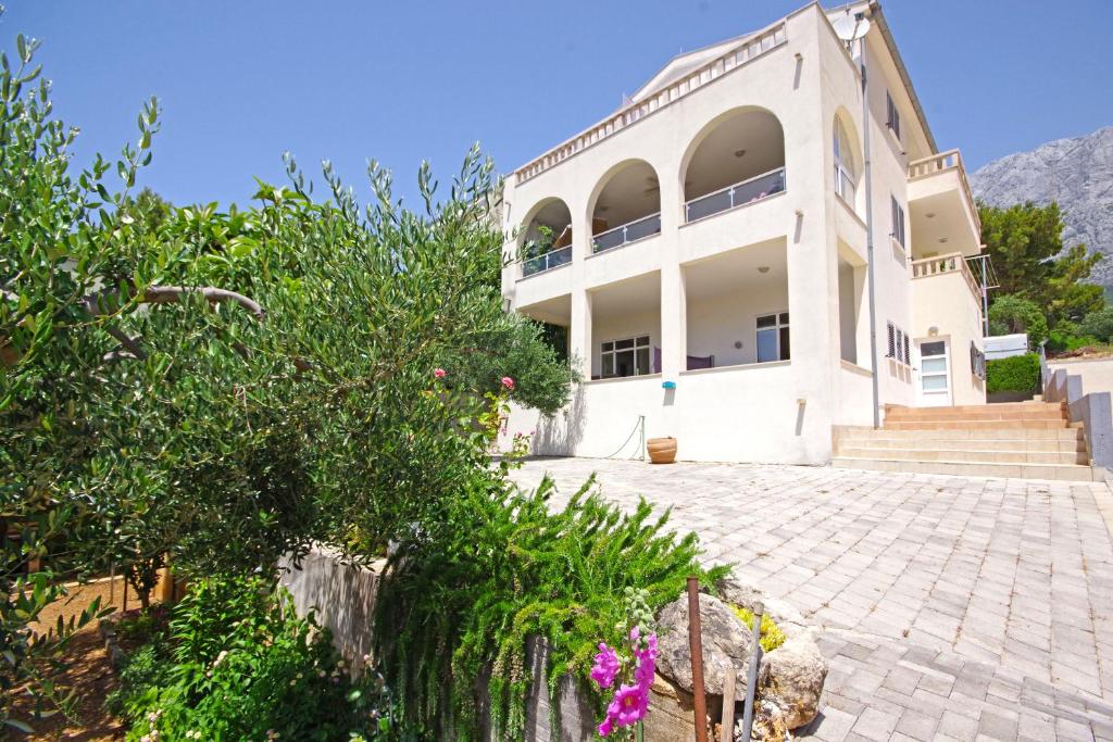 a large white building with trees and flowers at Apartmani Villa Antonio in Makarska