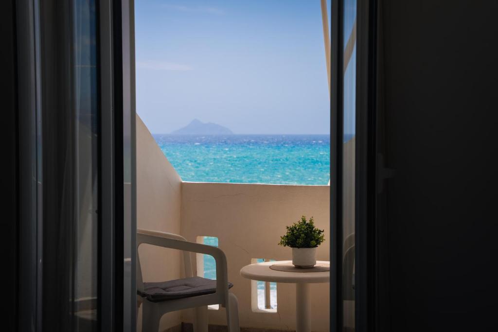 a view of the ocean from a room with a chair and a table at Nefeli Rooms with Sea View in Kalamaki in Kalamaki
