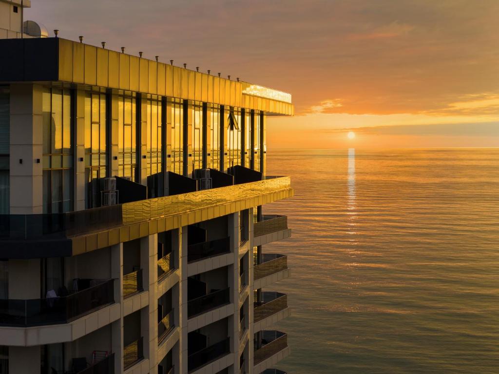 a building overlooking the ocean at sunset at Green Side Apart Hotel Official in Batumi