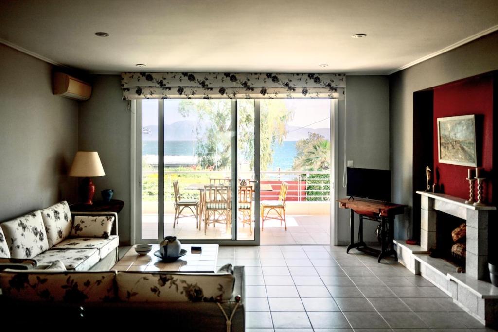 a living room with a couch and a sliding glass door at Aphrodite Residence - Seafront apartment, Melissi in Melíssion