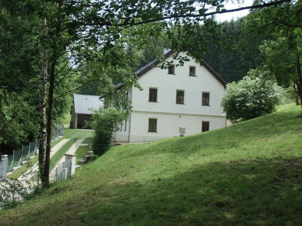 una casa blanca en la cima de una colina de hierba en Hájovna Bukovec, en Bukovec
