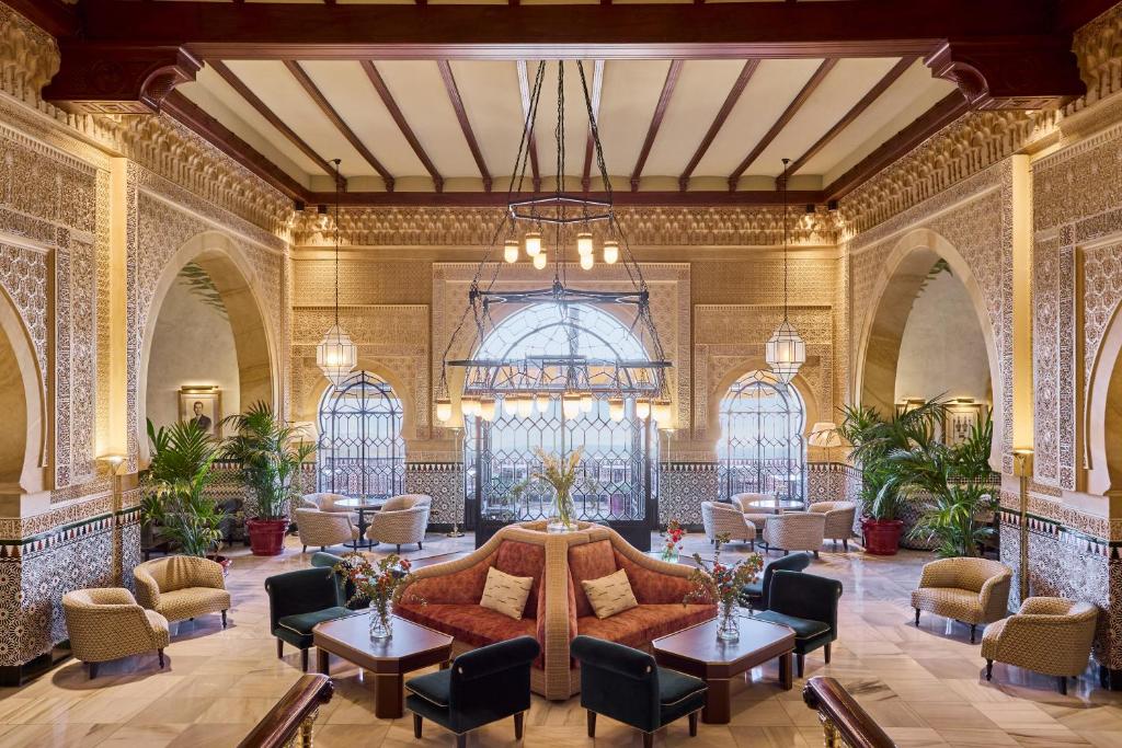 a lobby with a couch and tables and chairs at Alhambra Palace Hotel in Granada