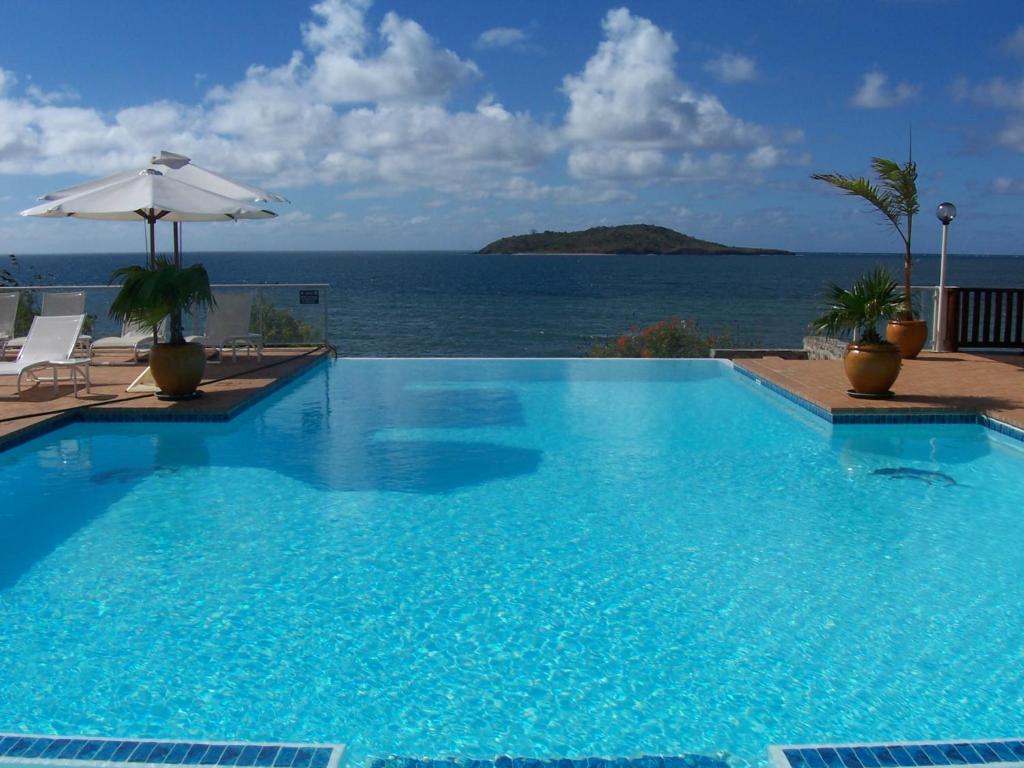 a large swimming pool with a view of the ocean at Hotel Sakouli in Bandrélé