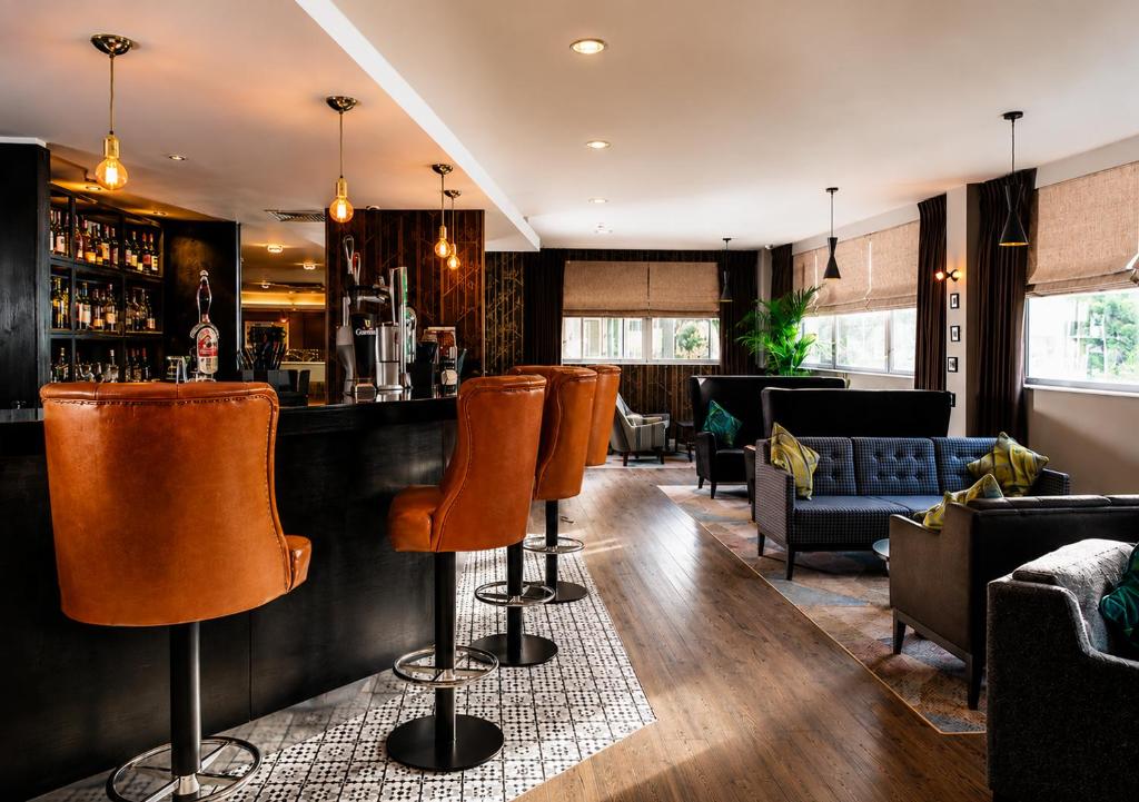 a bar with orange bar stools in a restaurant at Ramada Hotel & Suites by Wyndham Coventry in Coventry