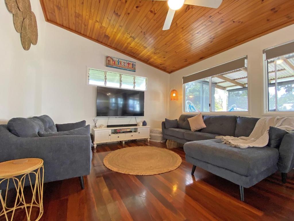 a living room with couches and a flat screen tv at Brownies on Birch in Amity Point