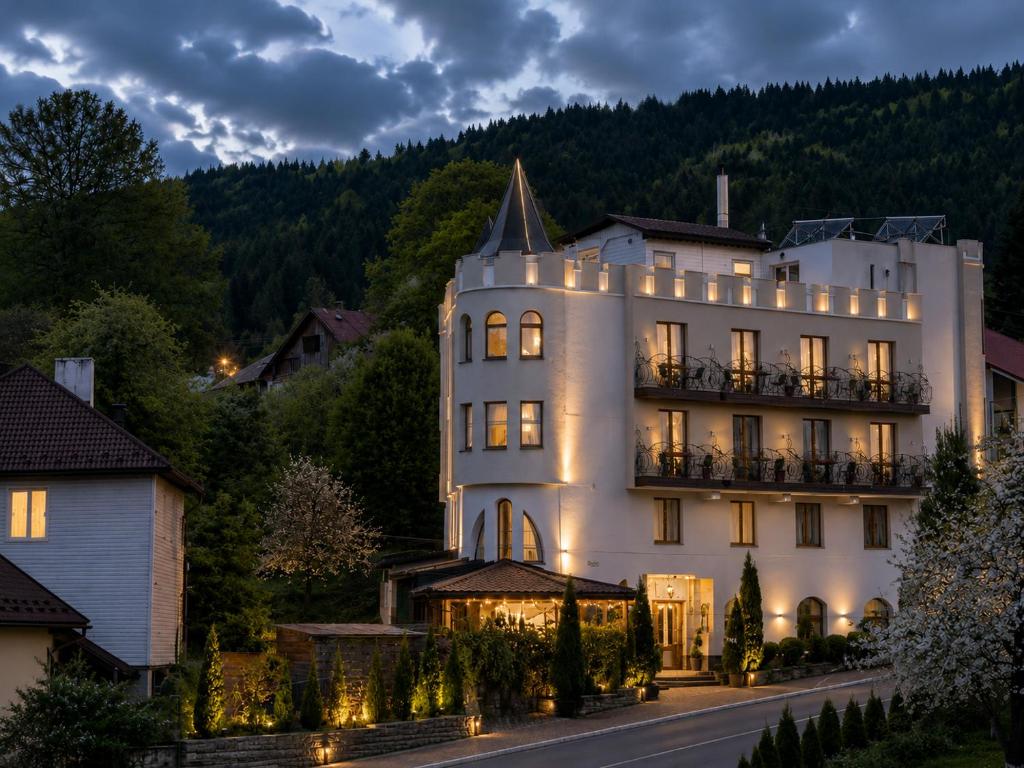 a large white building with lights on at Hotel Three Korony in Skhidnitsa