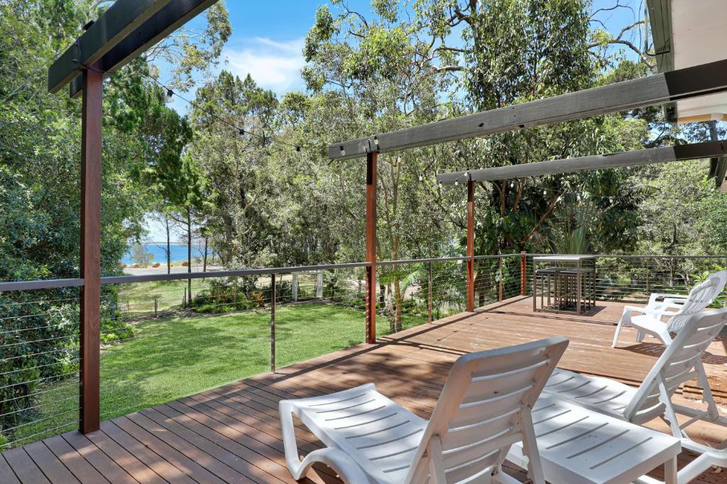 a deck with white chairs and a view of the water at Salty Beach in Amity Point