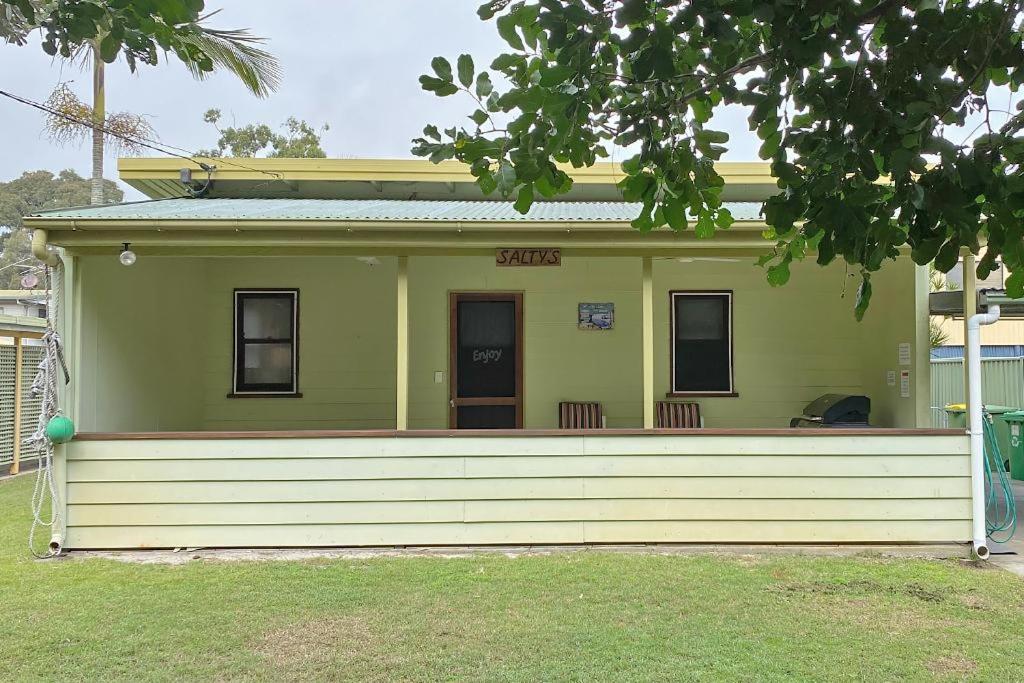 a small green house with a large front porch at Saltys Amity Point in Amity Point