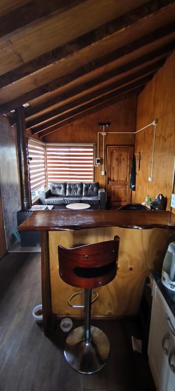 a kitchen with a bar with a chair at a counter at Cabañas Maullin in Maullín