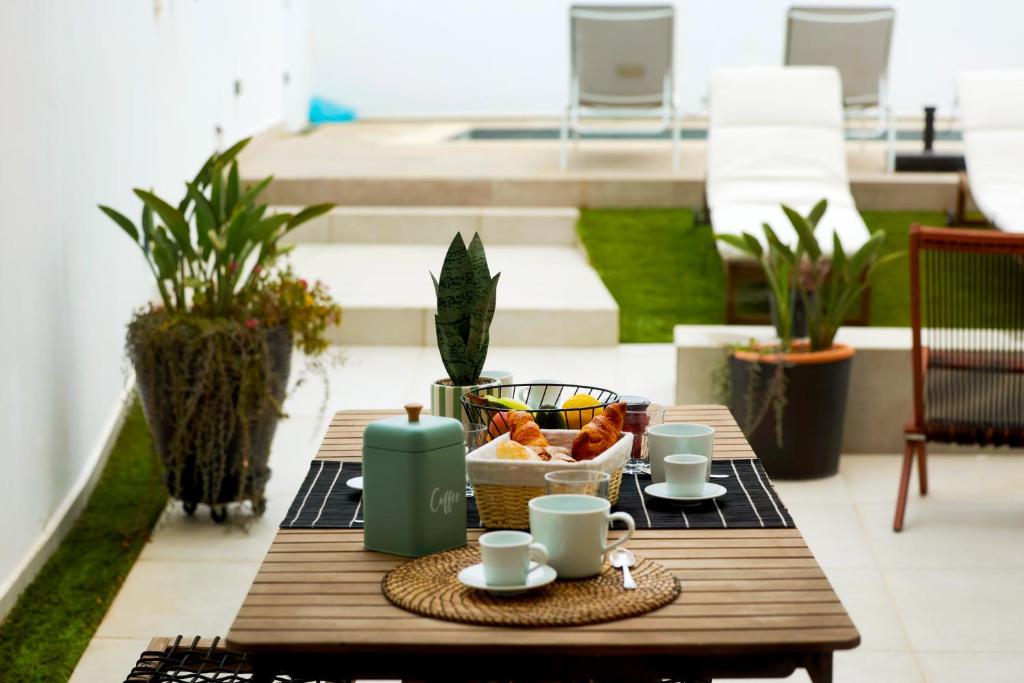a table with coffee cups and a basket of food on a patio at JB RiaMar l by Meditrust in Alvor