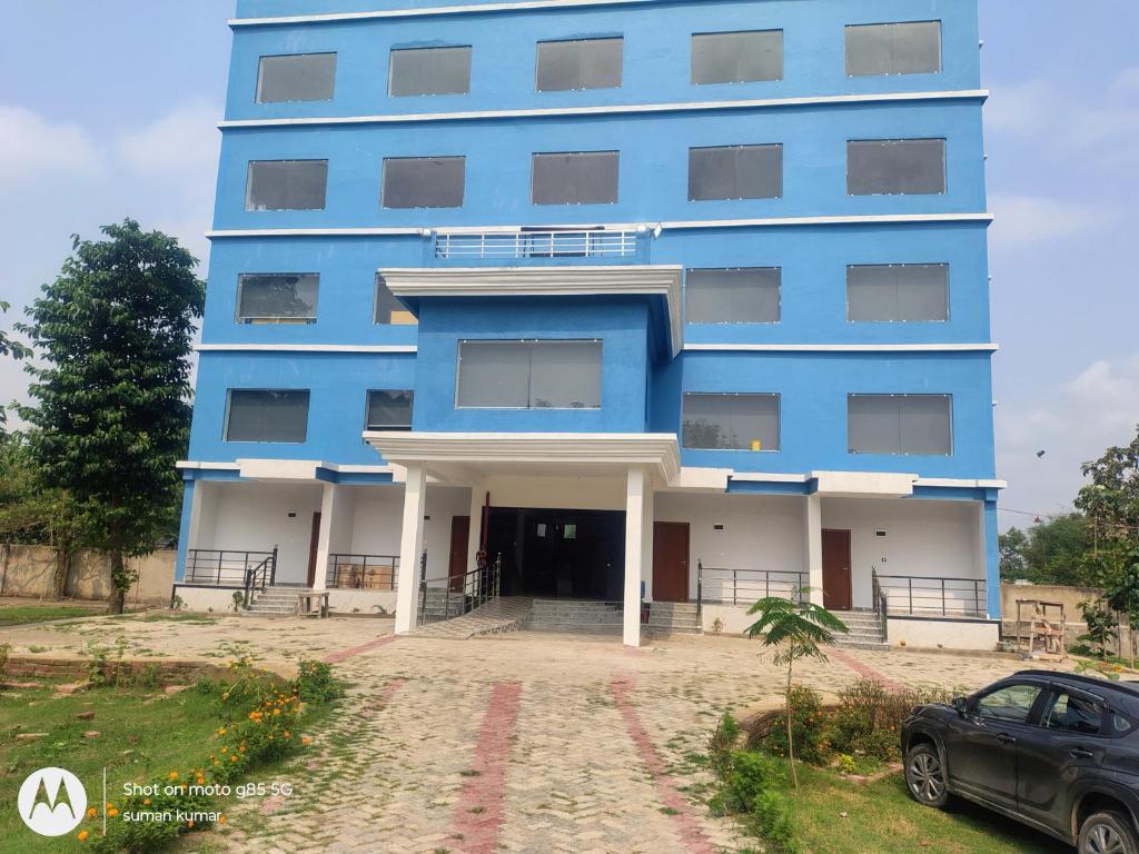 a blue building with a car parked in front of it at Chouhan Resort in Katihār