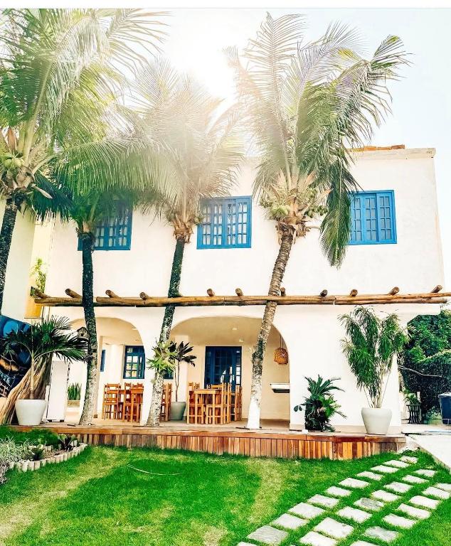 a house with palm trees in front of it at Pousada Areias do Pero in Cabo Frio