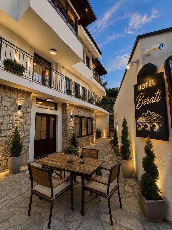 a patio with a wooden table and chairs in front of a building at Hotel Berati in Prizren