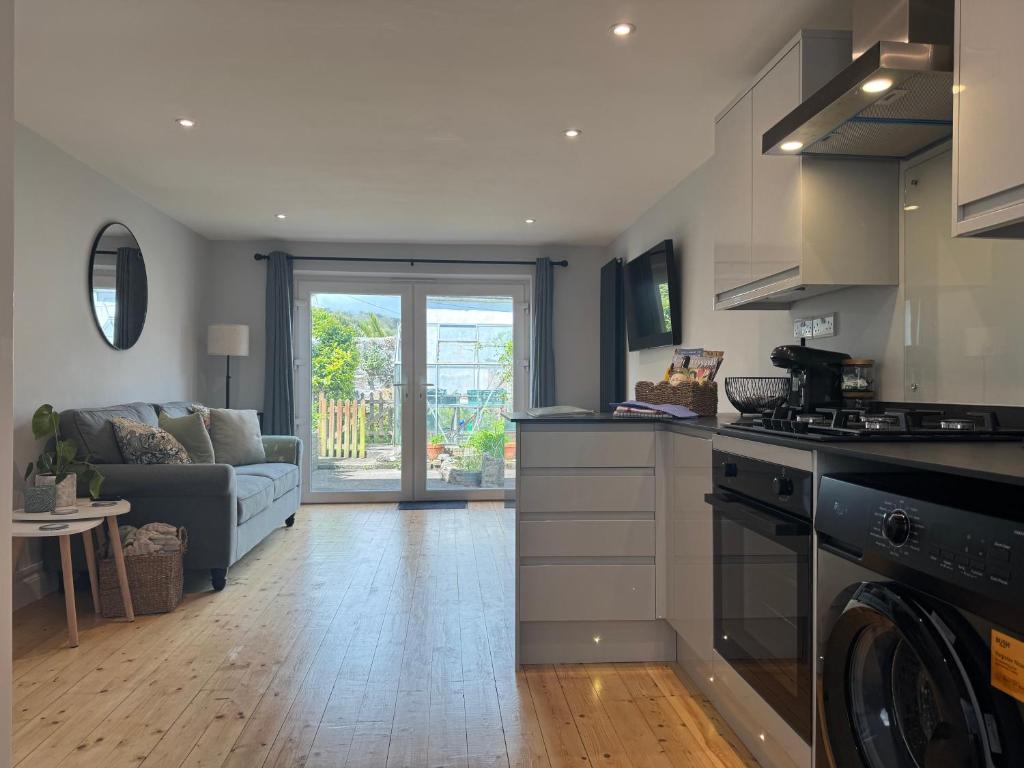 a kitchen and living room with a couch and a stove at 3 Harbour Lights, Newlyn in Penzance