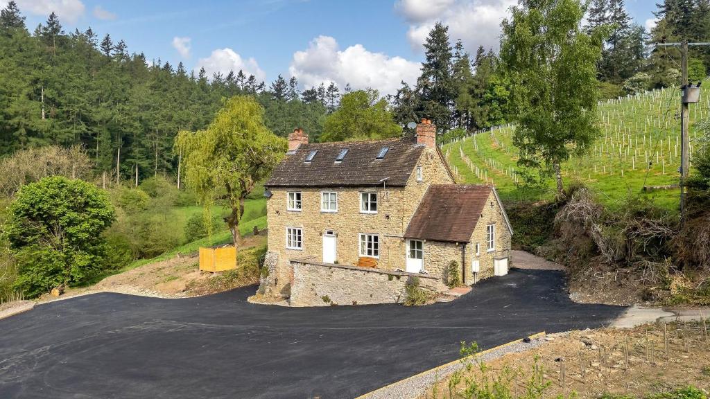 an old house on a hill with a road at Fernhalls Mill in Munslow