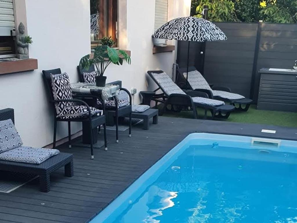 a patio with chairs and a pool and a table at Chambre cosy in Buhl