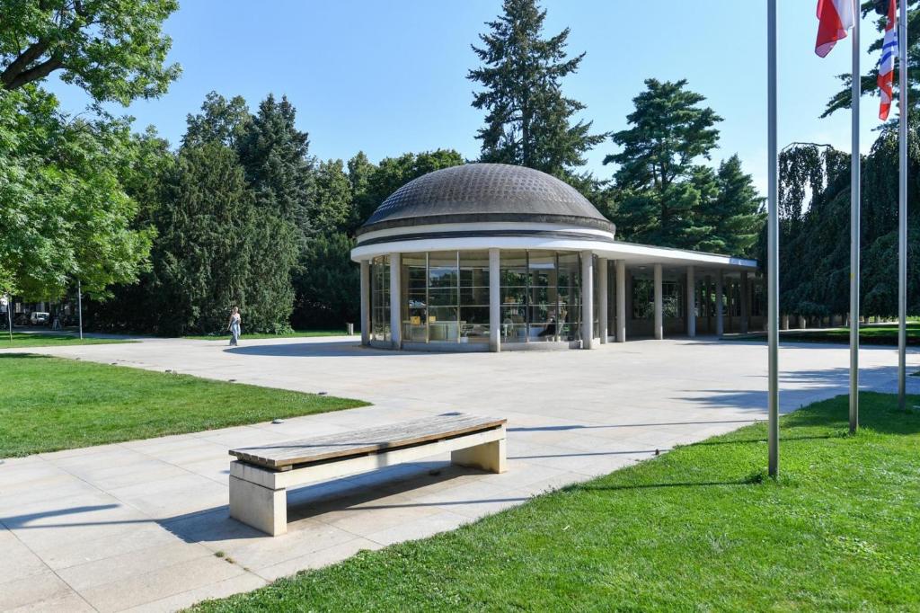 a building with a bench in a park at Apartmán Kolonáda in Poděbrady