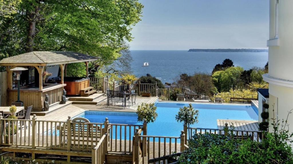 a swimming pool with a view of the water at Woodend Seaside Villa in Torquay