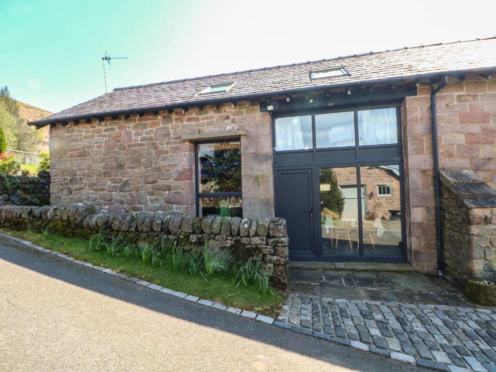 a stone house with a black door and windows at Pearls Farm One in Macclesfield