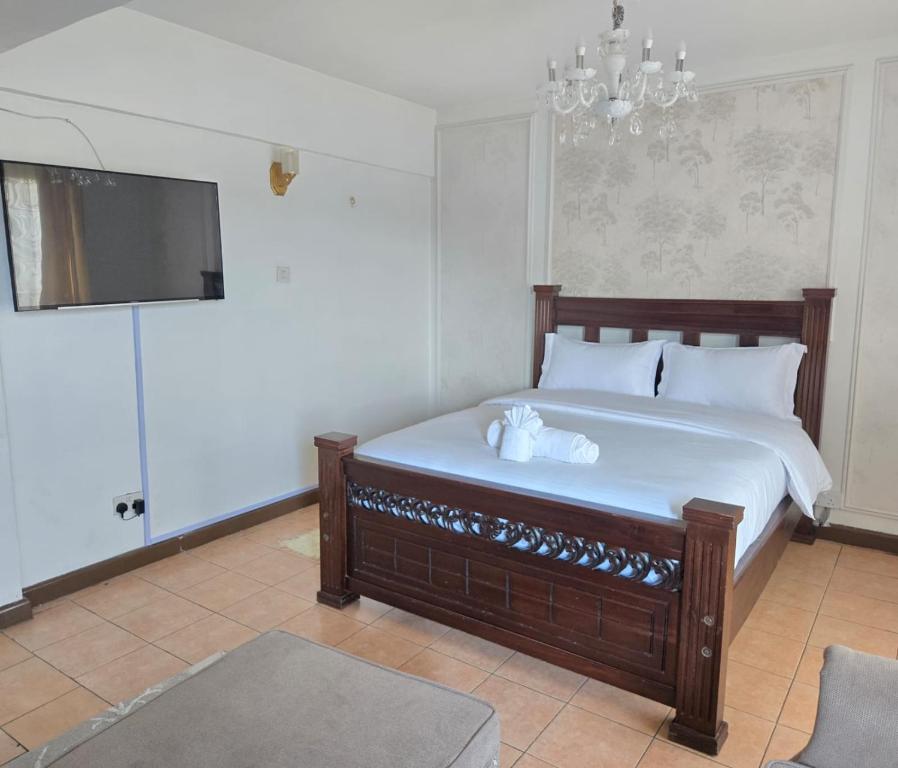 a bedroom with a bed with white sheets and a flat screen tv at Emeli Suites in Nairobi