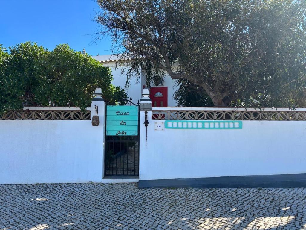 a white fence with a gate and a tree at Casa La Isla in Sagres