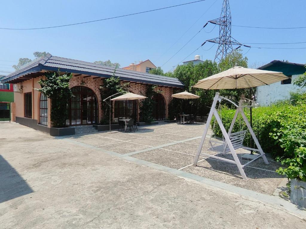 a patio with umbrellas in front of a building at The Doghouse in Dehradun