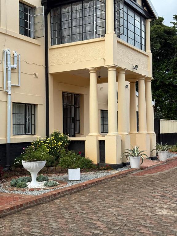 a building with columns and a white vase in front of it at Shukuru Guest House in Harare