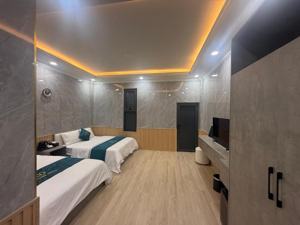 a hotel room with two beds and a television at Victory Hotel in Xóm Hương Phùng