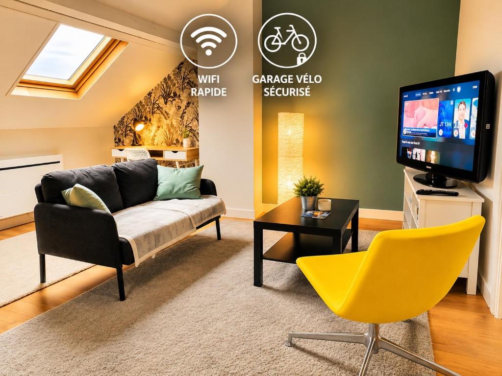 a living room with a couch and a tv at Appartement calme et spacieux, tout équipé in Saint-Quentin