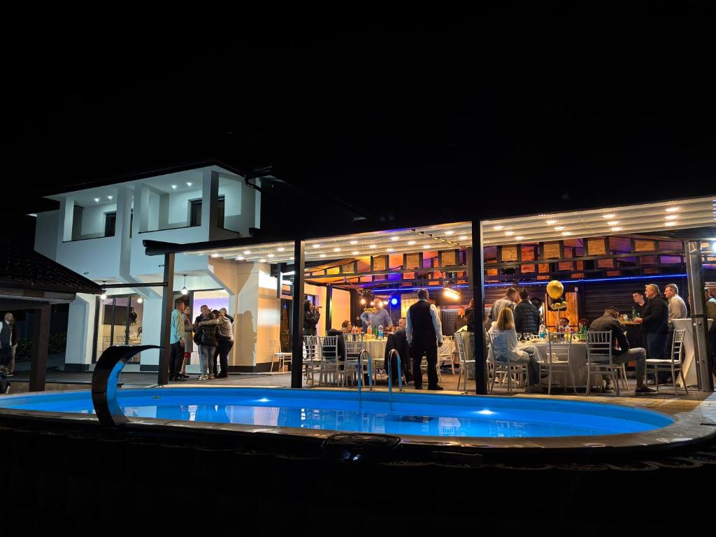 a swimming pool at night with people in a restaurant at Villa Tea - Private Pool Villa, Slatina in Laktaši