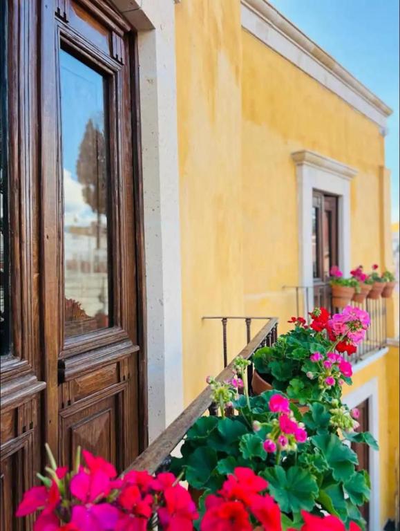 a balcony with red flowers and a window at Casa Luminara in Guanajuato