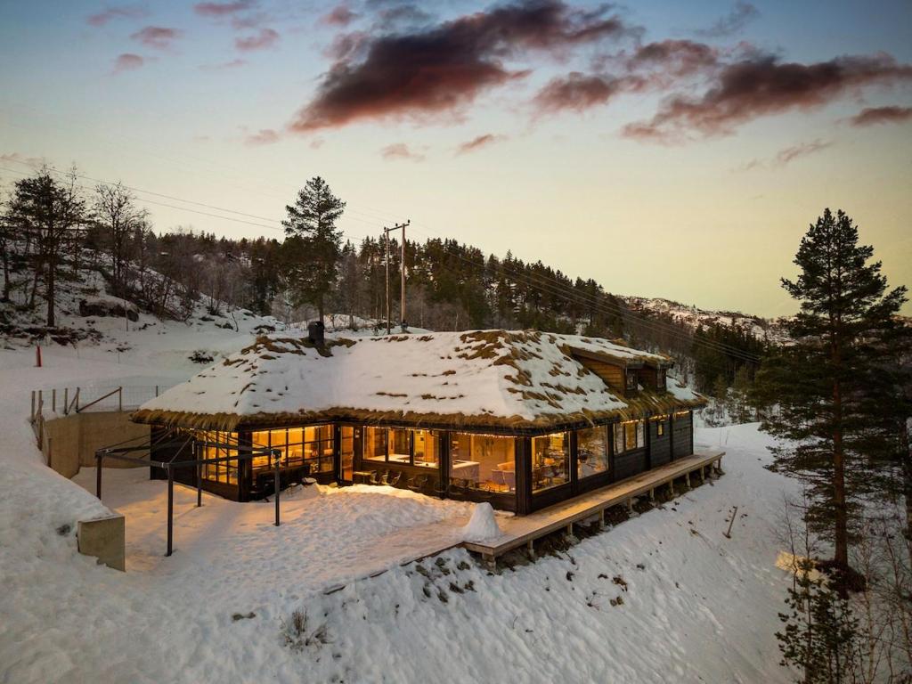 a house covered in snow with the sun shining on it at Large modern cabin from 2023 for rent in Dirdal