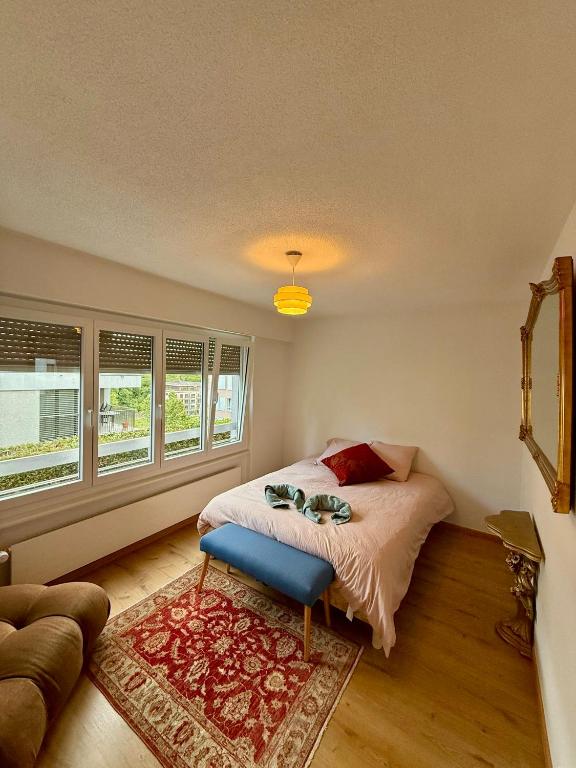 a bedroom with a bed with a blue stool in it at Studio chic et élégant avec Wi-Fi et Smart TV in Lausanne