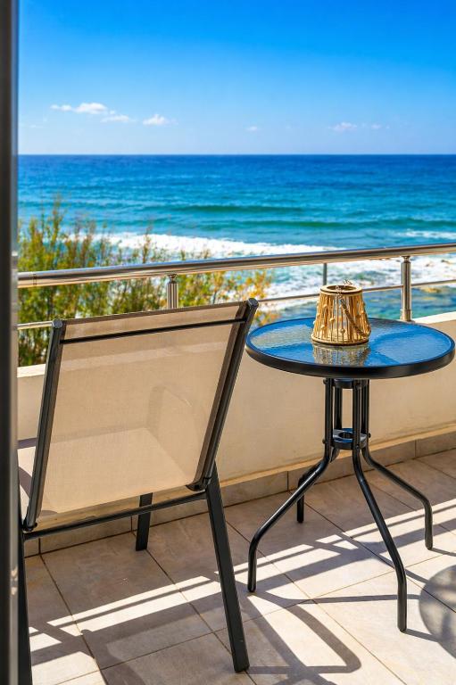 a table and a chair on a balcony with the ocean at Sole e Mare B2 Beachfront Sea View Apartment in Koutsourás