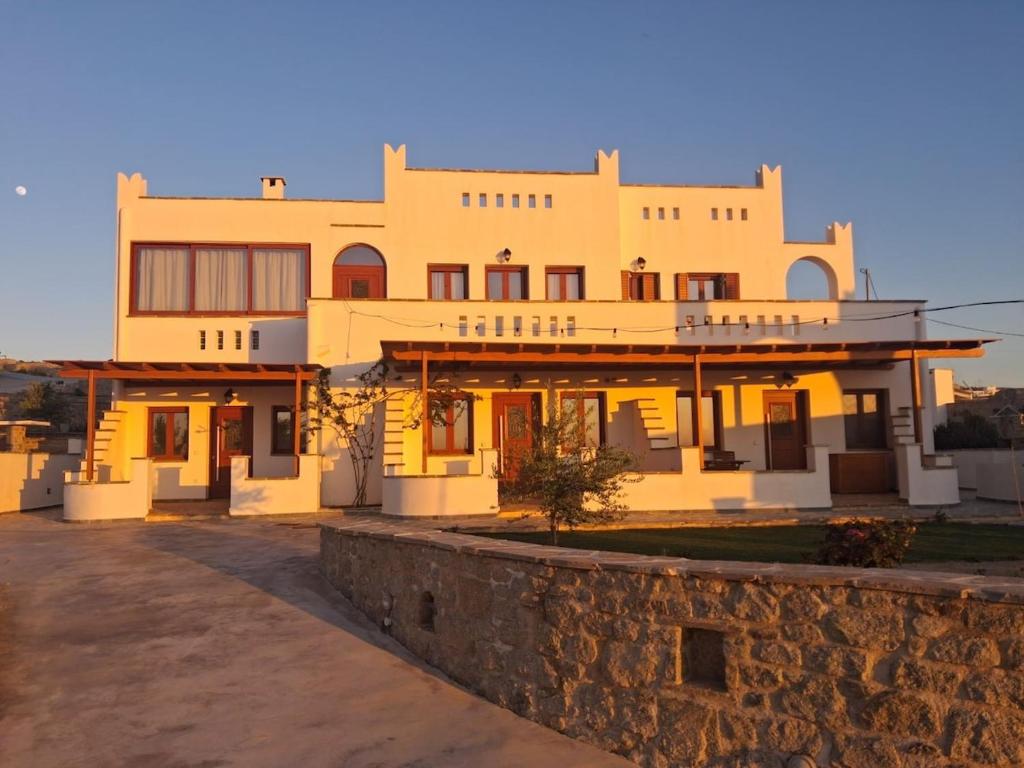 a large yellow building with a stone wall at Manolas Sunset View in Glinádhon