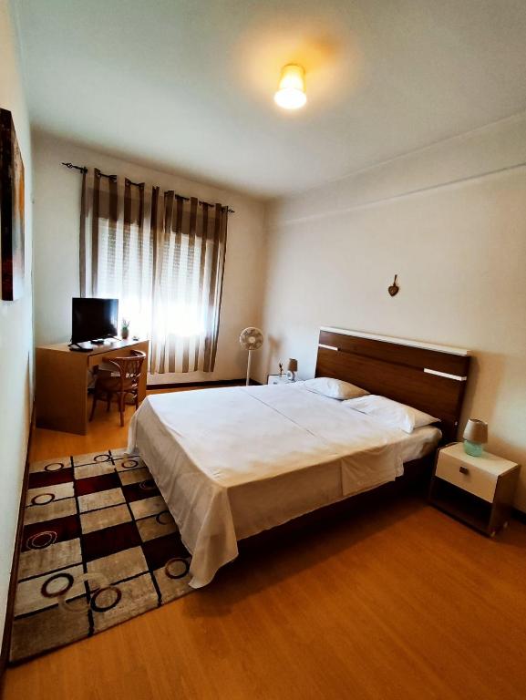 a bedroom with a large bed and a desk at Flor da Providência in Viseu