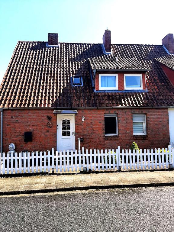 a red brick house with a white fence at Heide Nest Soltau in Soltau