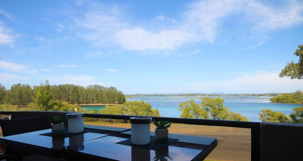 a table on a balcony with a view of a river at CHILL-OUT LAKESIDE - Wallis Lake Forster in Forster