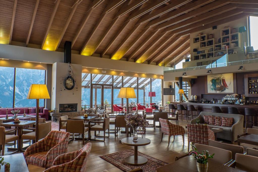 restauracja ze stołami, krzesłami i oknami w obiekcie Orizontes Tzoumerkon Hotel Resort w mieście Pramanta