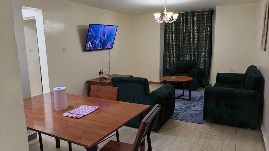 a living room with a wooden table and green chairs at Serenity Breeze in Ongata Rongai 