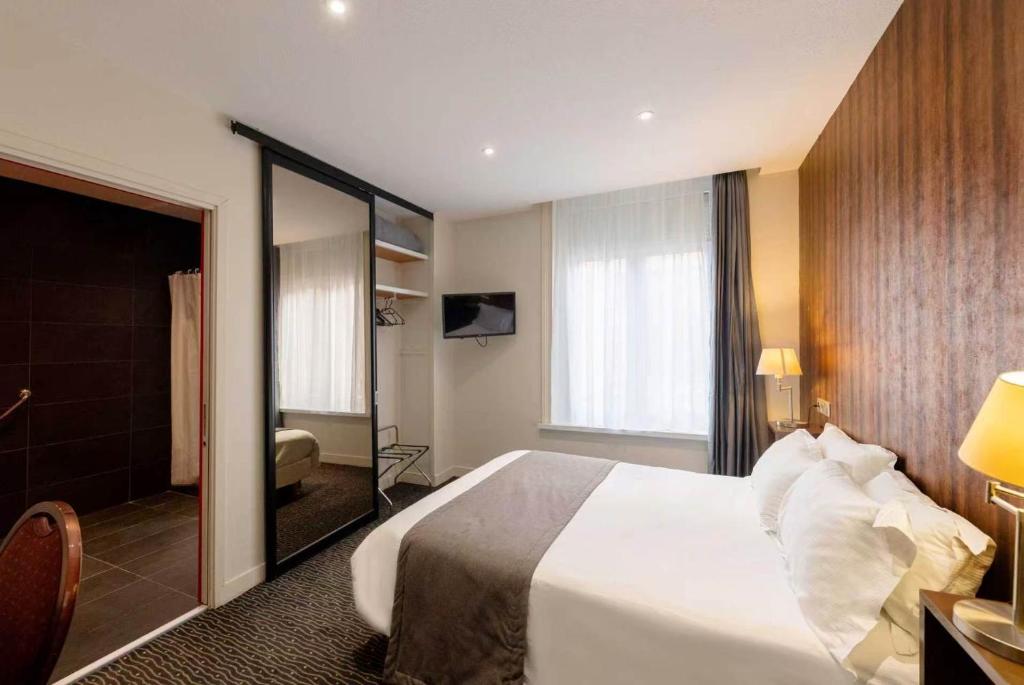 a hotel room with a large bed and a mirror at Metropol Hotel in Calais
