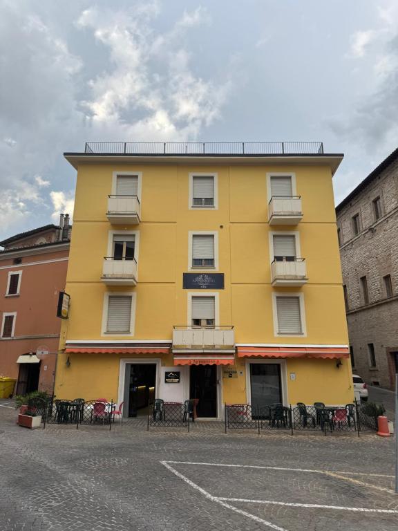 a yellow building with tables and chairs on a street at Hotel Appennino in Sassoferrato