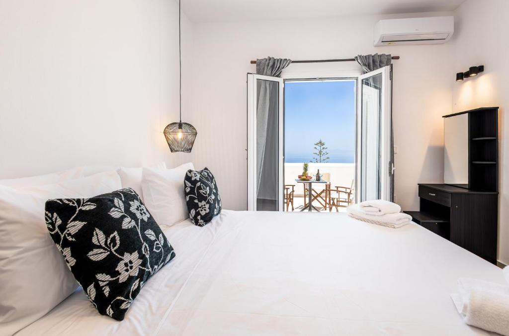 a bedroom with a white bed with a view of the ocean at Aurora Sky & Sea in Fira