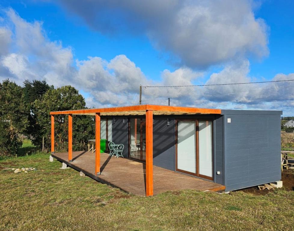a tiny house with an orange roof on a field at Tiny House en parcela de Puerto Varas in Puerto Varas