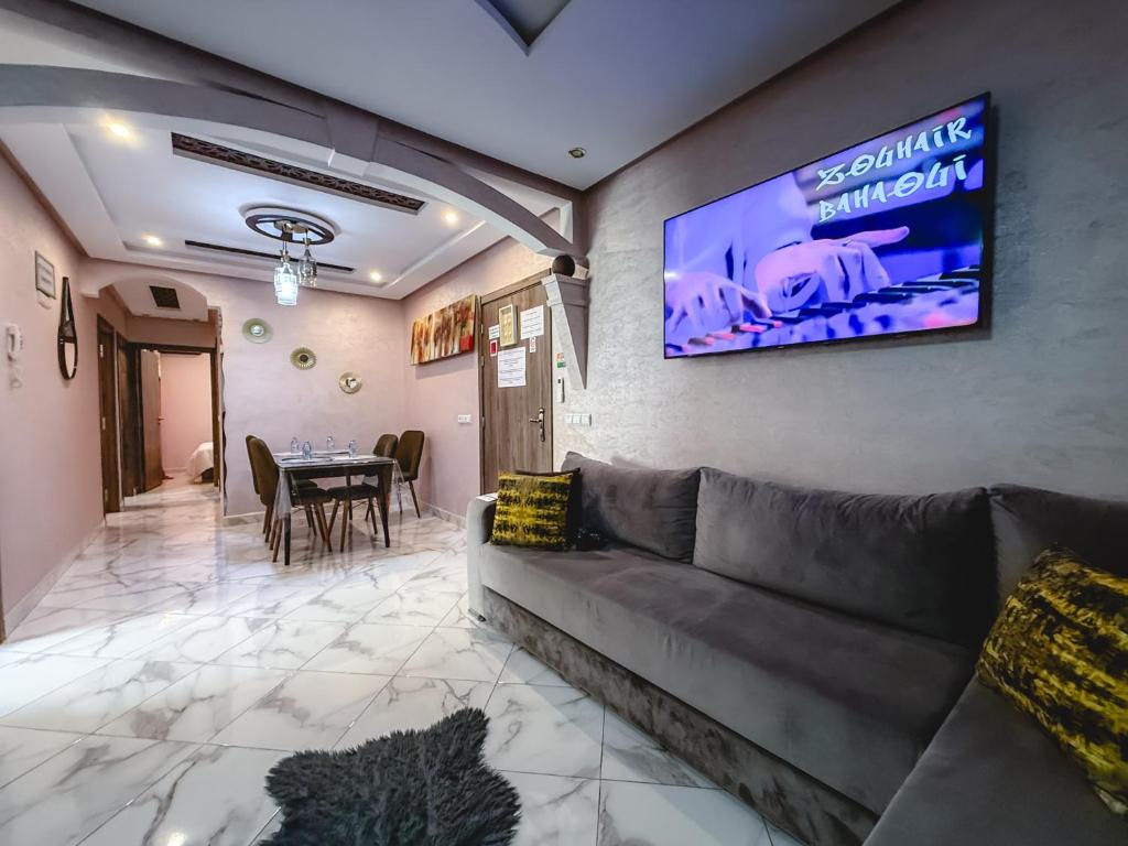 a living room with a couch and a tv on the wall at Les Jardins Anass 1 aéroport Marrakech in Marrakesh