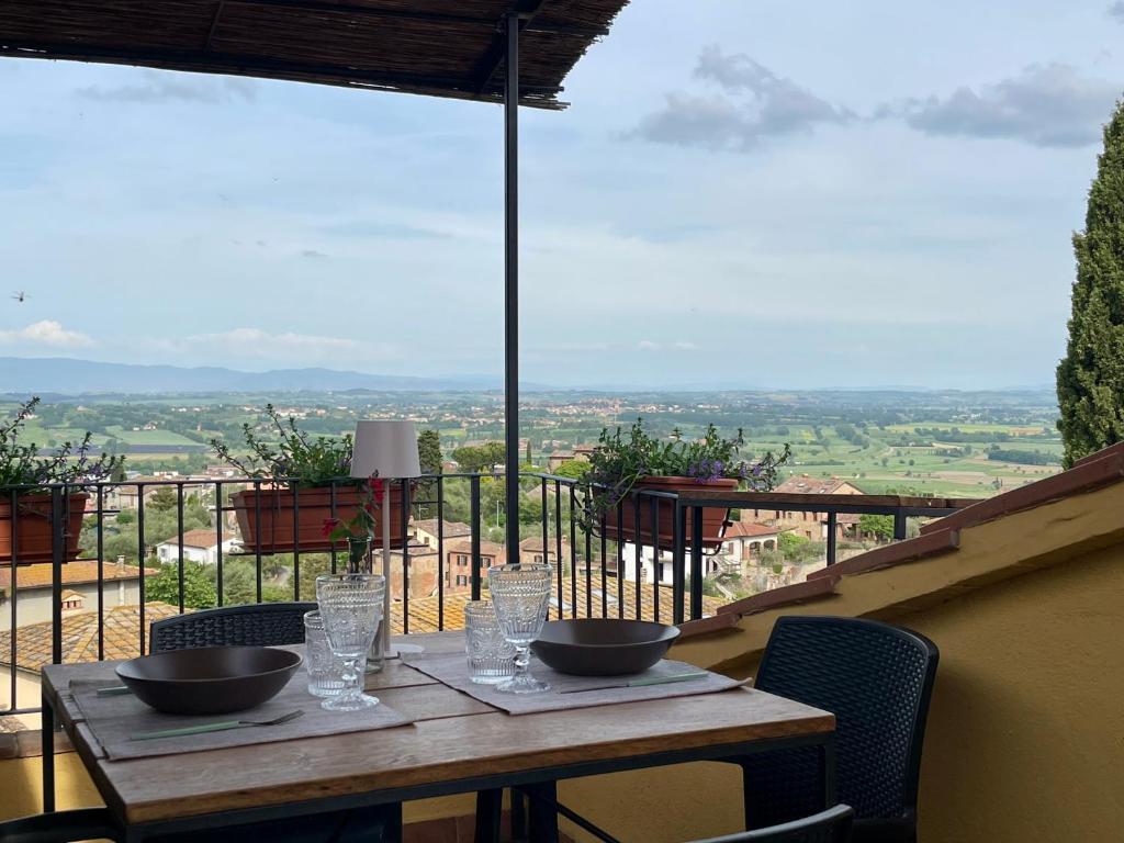 a wooden table with bowls and glasses on a balcony at Dimora 45, Contemporary Apartments in a Historic Building, Valdichiana, Tuscany in Sinalunga