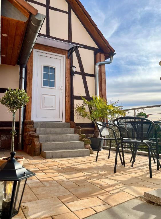 a patio with chairs and a white door and stairs at Ferienhaus Schwalmblick in Schwalmstadt