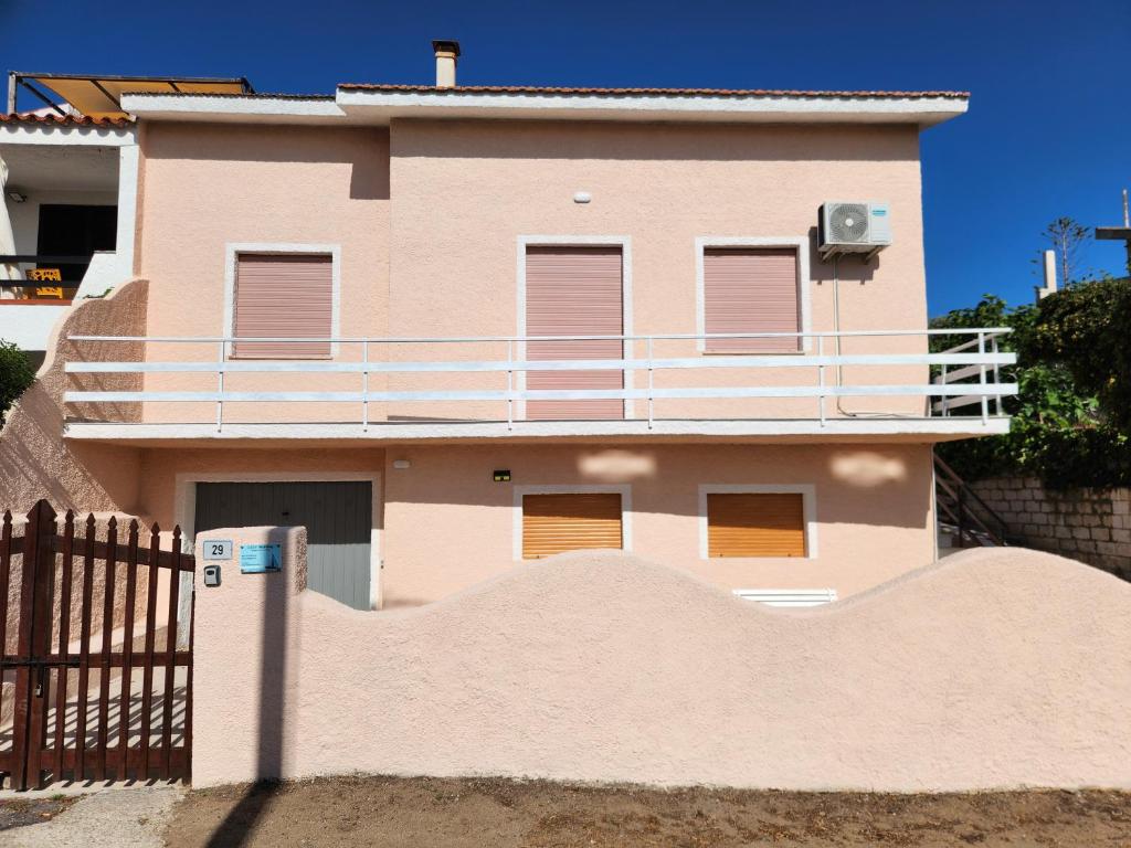 a pink house with a fence in front of it at Casa MedeFaby in S'archittu Cuglieri
