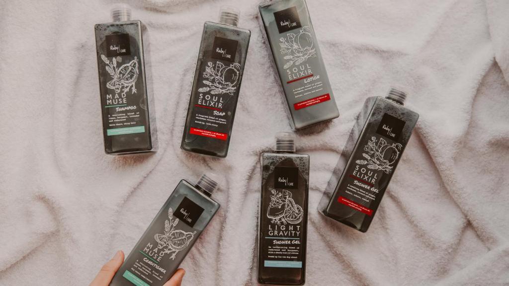 a person holding four hair products on a table at Ruby Frida Hotel Stockholm by IHG in Stockholm